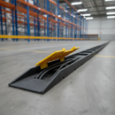 Black rubber 3 channel cable protector ramp with yellow lid open and cables inside, on a warehouse floor by pallet racking