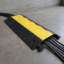 5 channel cable protector ramp in use on a concrete floor with five cables enclosed under the closed hi-vis yellow lids