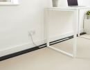 Black self-adhesive floor cable cover laid along a skirting board in a home office, hiding a power cable