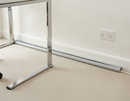 Grey self-adhesive floor cable cover laid along a skirting board next to a chrome desk leg