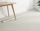 White self-adhesive floor cable cover running from a desk leg to a wall socket on light carpet