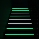 Photoluminescent anti-slip tape glowing green on staircase steps during power cut — emergency escape route visibility