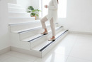 Anti-slip aluminium stair nosing with White PVC insert — installed on UK staircase with person using the stairs