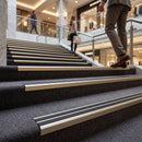 Champagne aluminium stair nosing with black rubber inserts on carpeted stairs in a shopping centre