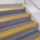 Satin Bronze double insert chevron stair nosing, 60mm riser with Yellow inserts, fitted on carpeted stairs