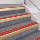 Satin Gold double insert chevron stair nosing, 60mm riser with Red inserts, fitted on carpeted stairs