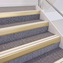 Satin Gold double insert chevron stair nosing, 60mm riser with White inserts, fitted on carpeted stairs