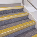 Satin Gold double insert chevron stair nosing, 60mm riser with Yellow inserts, fitted on carpeted stairs
