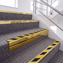 Mirrorflect Gold single insert chevron stair nosing, 65mm riser with Hazard black and yellow insert, fitted on carpeted stairs