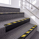 Satin Black single insert chevron stair nosing, 65mm riser with Hazard black and yellow insert, fitted on carpeted stairs