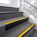 Satin Black single insert chevron stair nosing, 65mm riser with Yellow insert, fitted on carpeted stairs