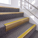 Satin Bronze single insert chevron stair nosing, 65mm riser with Yellow insert, fitted on carpeted stairs