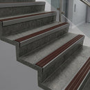 Raked back nosings with claret ribbed inserts on dark concrete steps beside a glass balustrade
