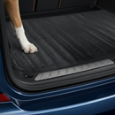Close-up of the ribbed non-slip texture and raised edge lip of the black rubber car boot liner mat with a dog's paw resting on it for scale