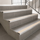 Slimline aluminium stair nosings with off-white anti-slip inserts on grey tiled staircase