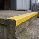 Yellow GRP stair nosing fitted to a weathered external concrete step at a loading bay