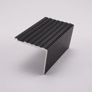 65x55mm raked back concealed fix aluminium stair nosing profile in black anodised on a plain studio background