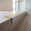 Raked back concealed fix aluminium stair nosing 65x55mm fitted to a concrete step, yellow cover strip