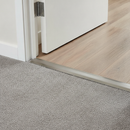 Z-profile carpet threshold installed at UK hallway doorway between carpet and laminate flooring