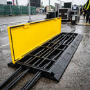 Five channel heavy duty cable protector ramp on wet tarmac with yellow hinged lid open showing five channels loaded with power cables