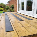 Dark grey 90mm fine grit GRP anti-slip decking strips on a raised patio deck by patio doors