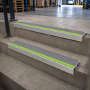 Two aluminium stair nosings with dolphin grey and green anti-slip inserts fitted to concrete warehouse steps