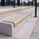 Satin gold 84mm double channel bullnose aluminium stair nosing with twin Everest light grey gritted exterior-grip inserts fitted on leisure centre entrance steps