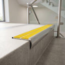 Bullnose double channel aluminium stair nosing 98x40mm fitted to a concrete step in an office stairwell, twin Yellow Castellated inserts