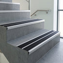 Aluminium stair nosing 90x32mm double channel fitted to a concrete step - Mill Aluminium finish with twin Black Castellated inserts