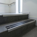 Aluminium stair nosing 90x32mm double channel fitted to a concrete step - Mill Aluminium finish with twin Black Smooth Textured inserts