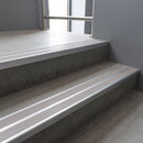 Aluminium stair nosing 90x32mm double channel fitted to a concrete step - Mill Aluminium finish with twin Light Grey Castellated inserts
