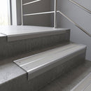 Aluminium stair nosing 90x32mm double channel fitted to a concrete step - Mill Aluminium finish with twin Light Grey Smooth Textured inserts