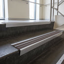 Aluminium stair nosing 90x32mm double channel fitted to a concrete step - Mill Aluminium finish with twin Peat Castellated inserts