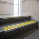 Aluminium stair nosing 90x32mm double channel fitted to a concrete step - Mill Aluminium finish with twin Yellow Castellated inserts