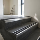 Aluminium stair nosing 90x32mm double channel fitted to a concrete step - Polished Aluminium finish with twin Black Castellated inserts