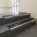 Aluminium stair nosing 90x32mm double channel fitted to a concrete step - Polished Aluminium finish with twin Black Smooth Textured inserts