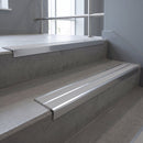 Aluminium stair nosing 90x32mm double channel fitted to a concrete step - Polished Aluminium finish with twin Polar Grey Castellated inserts