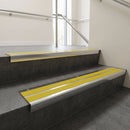 Aluminium stair nosing 90x32mm double channel fitted to a concrete step - Polished Aluminium finish with twin Yellow Castellated inserts