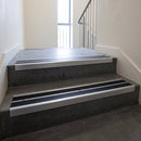 Aluminium stair nosing 90x32mm double channel fitted to a concrete step - Satin Aluminium finish with twin Black Smooth Textured inserts