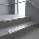 Aluminium stair nosing 90x32mm double channel fitted to a concrete step - Satin Aluminium finish with twin Polished Aluminium inserts