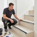 Professional fitter installing aluminium stair nosing on tiled staircase UK