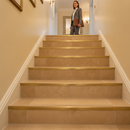 Heavy duty tile-in stair nosing in Beige — real-life installation on tiled UK staircase with person using the stairs