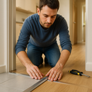 Homeowner installing 26mm aluminium T-bar floor transition strip between tiles and laminate flooring in UK home - DIY installation