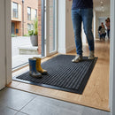 Grey ribbed polypropylene entrance doormat in modern home entryway with person standing on mat