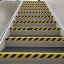 Black/yellow hazard GRP stair tread covers on commercial staircase — DDA high-visibility full tread coverage