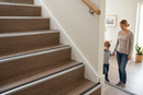 Anti-slip bullnose stair nosing with grey insert installed on UK home laminate staircase - mother and child using stairs safely