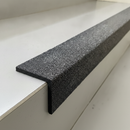 Close-up of black GRP stair nosing 55x55mm showing impregnated quartz grit surface and L-profile installation