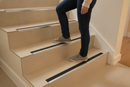 Anti-slip aluminium stair nosing with Beige PVC insert — installed on UK staircase with person using the stairs