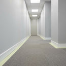 Photoluminescent egress marking tape applied along the skirting board of an office corridor under normal lighting