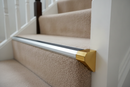 Bright gold anodised aluminium stair nosing end cap fitted to a carpeted staircase edge in a UK home hallway